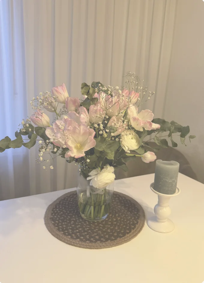 A pink and white floral bouquet styled on a dining table