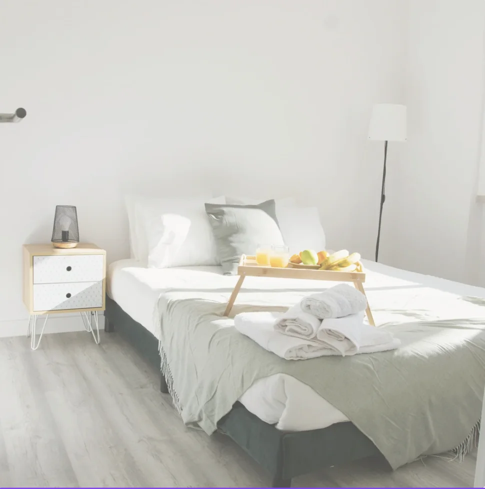 A guest-ready bedroom with fresh towels and a welcome tray