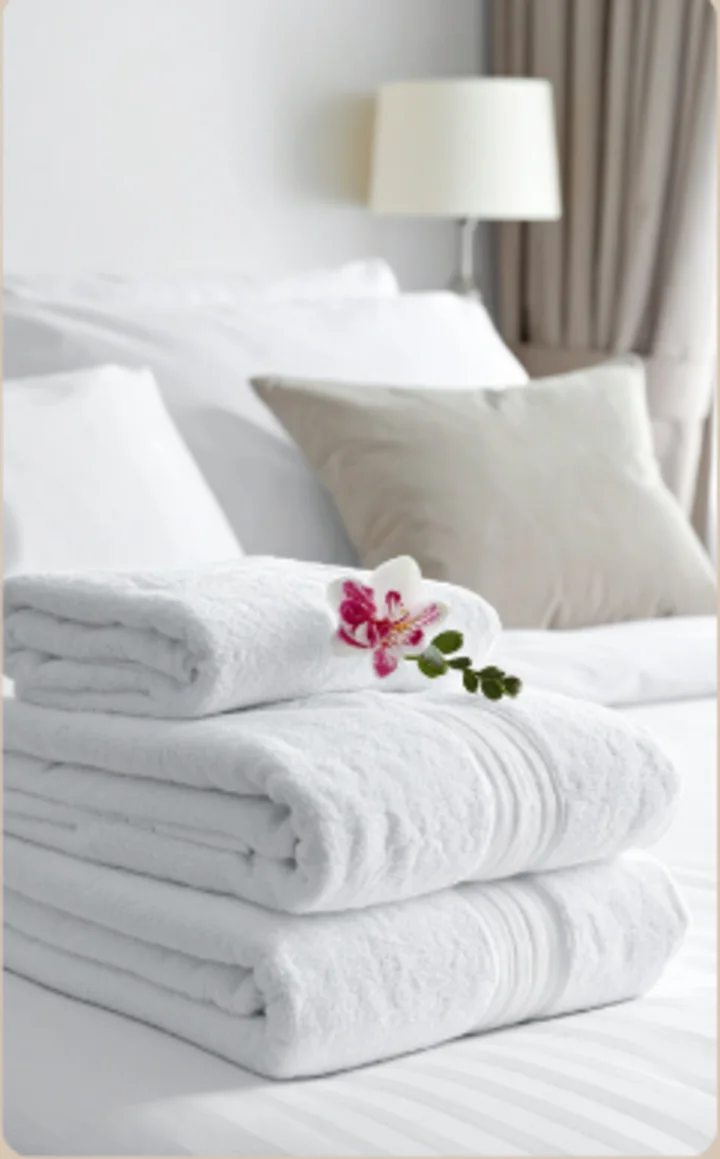 Freshly folded white towels on a guest bed